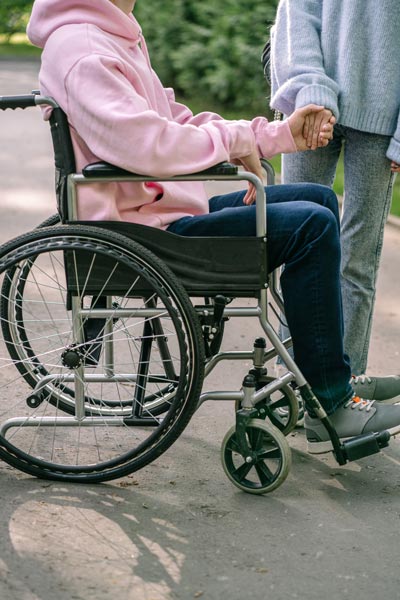 Acompañante sosteniendo la mano de una persona en silla de ruedas
